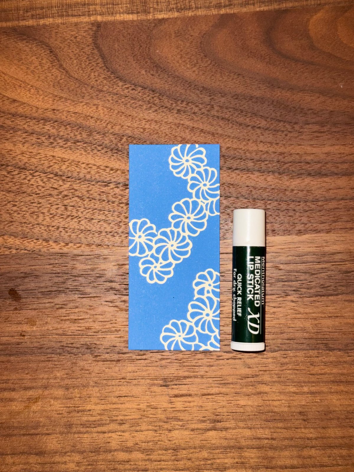 Un pochi-bukuro Haibara bleu posé à côté d'un stick de baume à lèvres pour montrer la taille