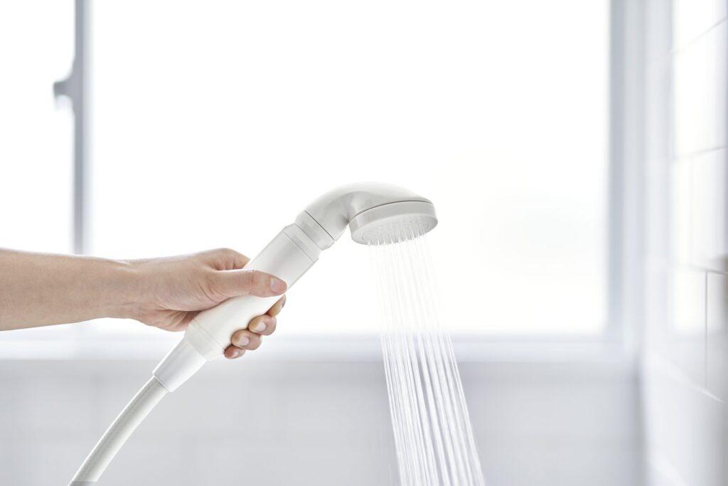 Pommeau de douche ionac tenu en main, jet d'eau en marche